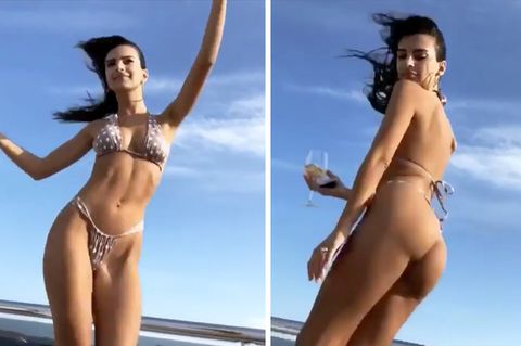 Supermodel Emily Ratajkwoski tanzt im knappen, gepunkteten Bikini auf einer Yacht und hält ein Weinglas in der Hand