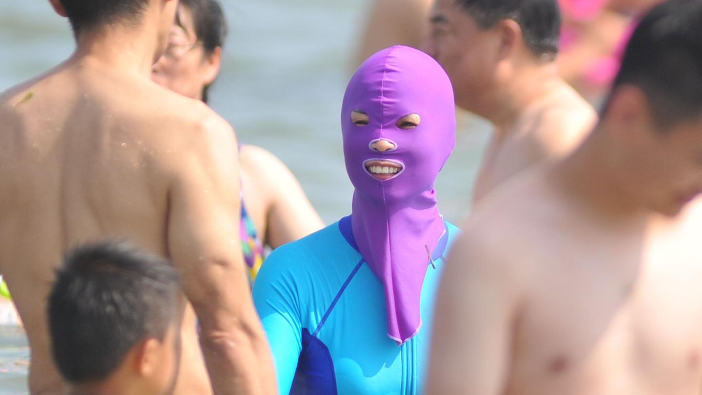 Eine Frau steht mit einem Facekini im Wasser