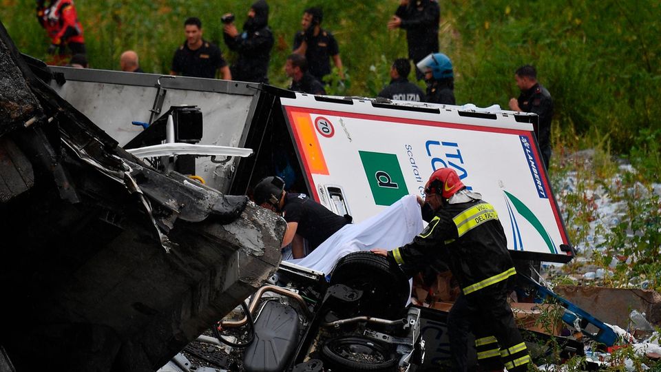 Feuerwehrleute suchen zwischen zerstörten Autos und großen Betonteilen nach Opfern des Einsturzes einer Autobahnbrücke in Genua