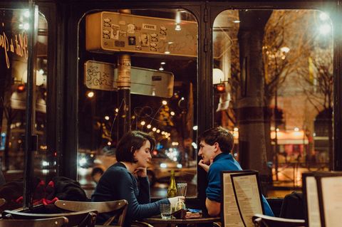 Ein Mann und eine Frau sitzen sich an einem Café-Tisch gegenüber