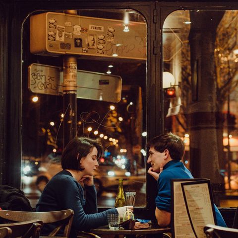 Ein Mann und eine Frau sitzen sich an einem Café-Tisch gegenüber
