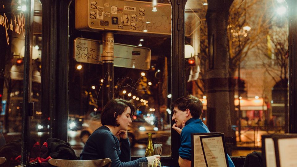 Ein Mann und eine Frau sitzen sich an einem Café-Tisch gegenüber