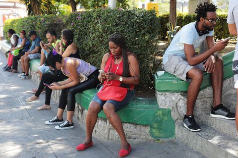 Kubaner sitzen an einem Wifi-Hotspot und surfen im Internet