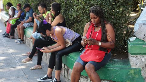 Kubaner sitzen an einem Wifi-Hotspot und surfen im Internet