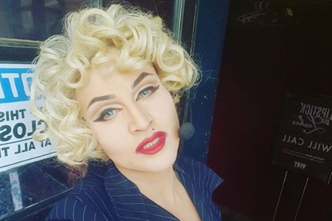 Adam Guerra geschminkt und verkleidet als Madonna, posiert mit lockigen Haaren und strengem Blazer
