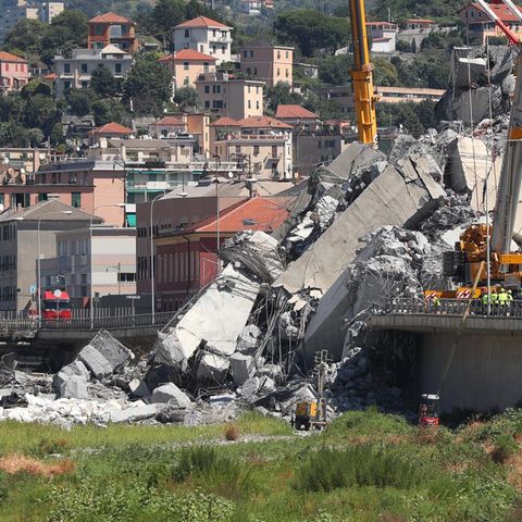 Italien, Genua: Mit Baggern und Kränen werden Trümmerteile einer teilweise eingestürzten Brücke weggeräumt.