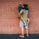 Zwei Menschen küssen sich vor einer Mauer