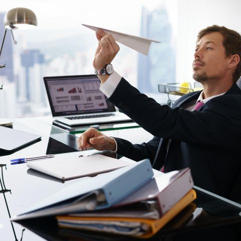Mann imBüro hält einen Papierflieger in der Hand