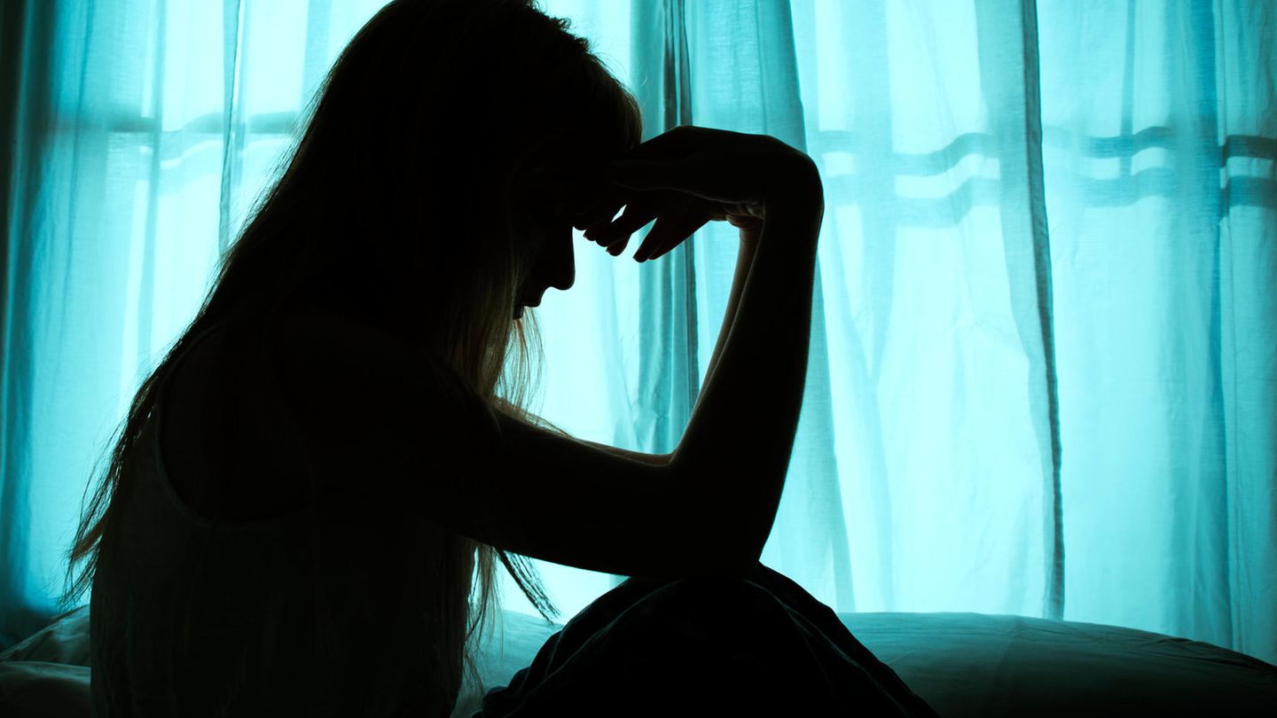 Eine Frau sitzt im Dunkeln vor einem Fenster