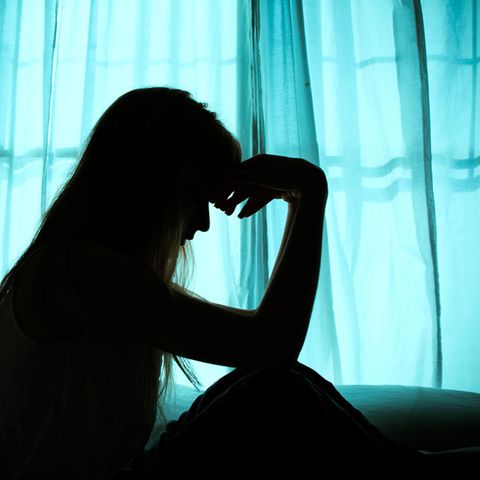 Eine Frau sitzt im Dunkeln vor einem Fenster