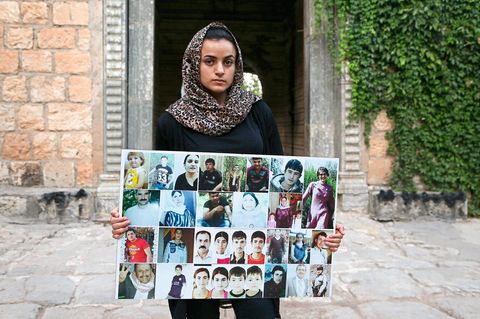 Aschwaq Taloo zeigt vor dem Lalisch-Schrein im Nordirak Bilder von Opfern aus ihrem Dorf