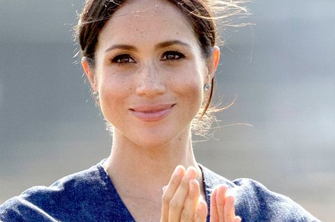 Im blauen Sommerkleid lächelt Herzogin Meghan von Sussex und klatscht in die Hände