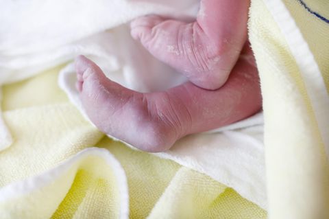Ein Neugeborenes liegt eingewickelt in eine Decke auf einem Wickeltisch