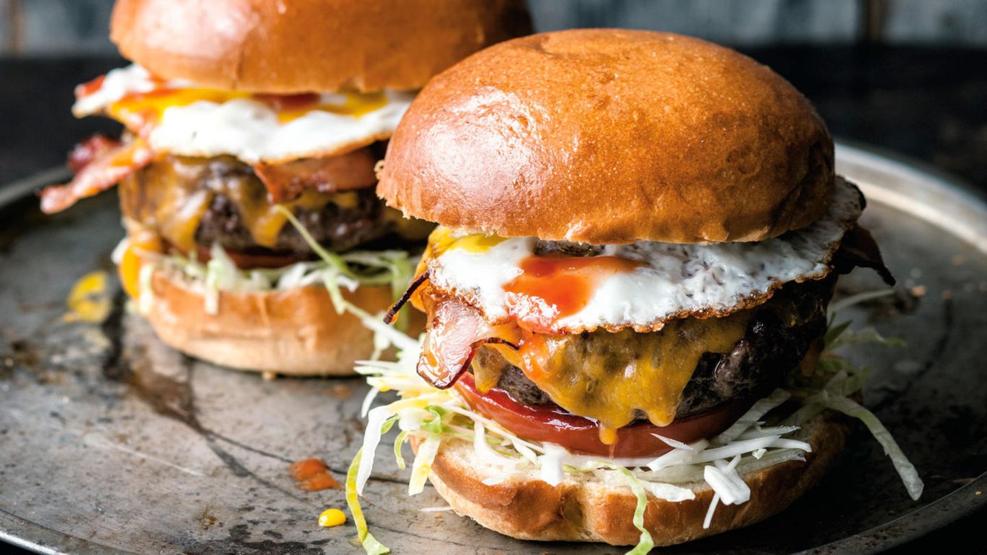 Ein Burger mit Kohl, Salat, Tomate, Fleisch, Bacon und Spiegelei