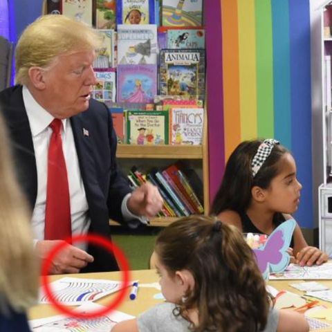 US-Präsident Donald Trump sitzt mit mehreren Kindern an einem Tisch und malt eine US-Flagge aus. Ein Streifen ist blau