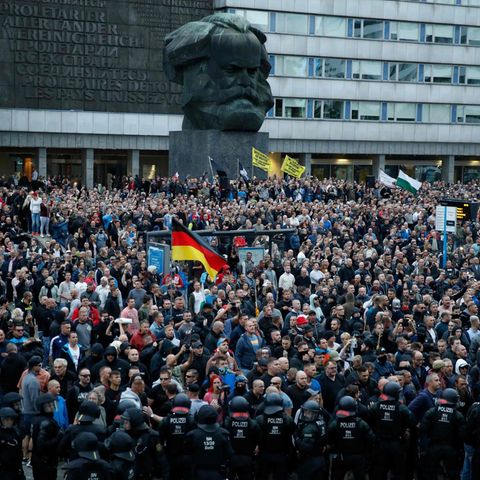 Demonstranten der rechten Szene stehen vor dem Karl-Marx-Denkmal in Chemnitz