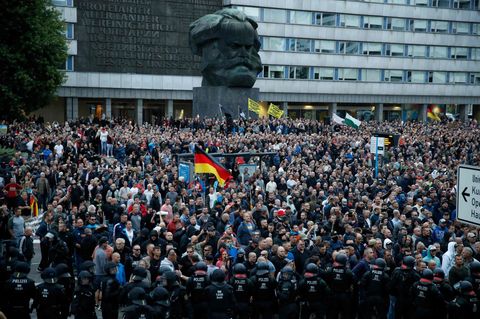 Demonstranten der rechten Szene stehen vor dem Karl-Marx-Denkmal in Chemnitz