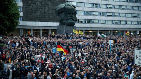 Demonstranten der rechten Szene stehen vor dem Karl-Marx-Denkmal in Chemnitz