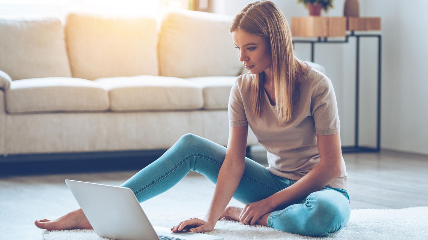 Eine Frau sitzt mit ihrem Laptop vor der Couch