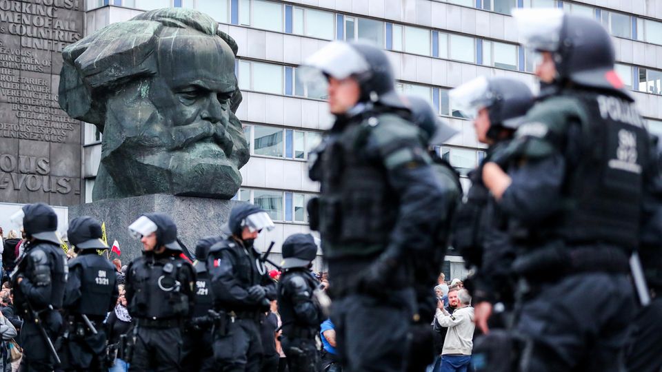 Polizei steht nach den rechten Krawallen unter der Karl-Marx-Büste in Chemnitz