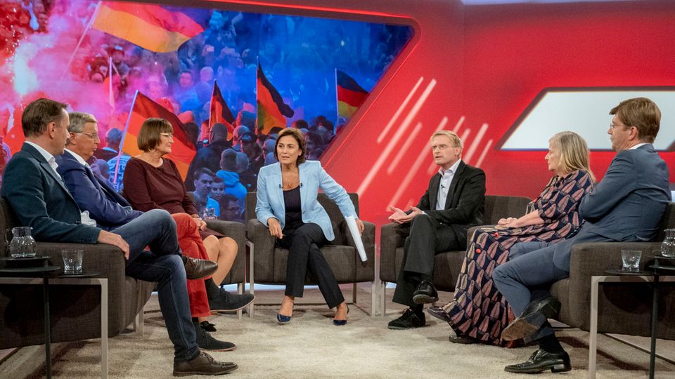 In einem TV-Studio sitzt Sandra Maischberger in der Mitte, links von ihr zwei Männer und eine Frau, rechts ebenfalls