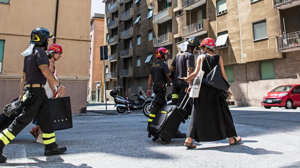 Italien: Die Feuerwehr begleitet zwei Genueserinnen zu ihren Wohnungen. Die Evakuierungen werden immer wieder unterbrochen – aus Angst vor einem weiteren Einsturz Die Feuerwehr begleitet zwei Genueserinnen zu ihren Wohnungen. Die Evakuierungen werden immer wieder unterbrochen – aus Angst vor einem weiteren Einsturz