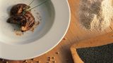 Schlutzkrapfen  Ein Koch serviert die typischen Tiroler Teigtaschen mit Bockshörndlmehl und Mohn. Gibt es auch in der weniger fancy Version mit Spinat und Topfen, also Quark, oder Rüben-Speck-Füllung in jedem guten Tiroler Gasthof.