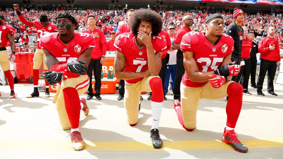 Die Geste, die ihn (und andere Sportler) berühmt gemacht hat: Colin Kaepernick (M.), Eli Harold (l.), und Eric Reid während der Nationalhymne vor dem Spiel der San Francisco 49ers gegen die Dallas Cowboys