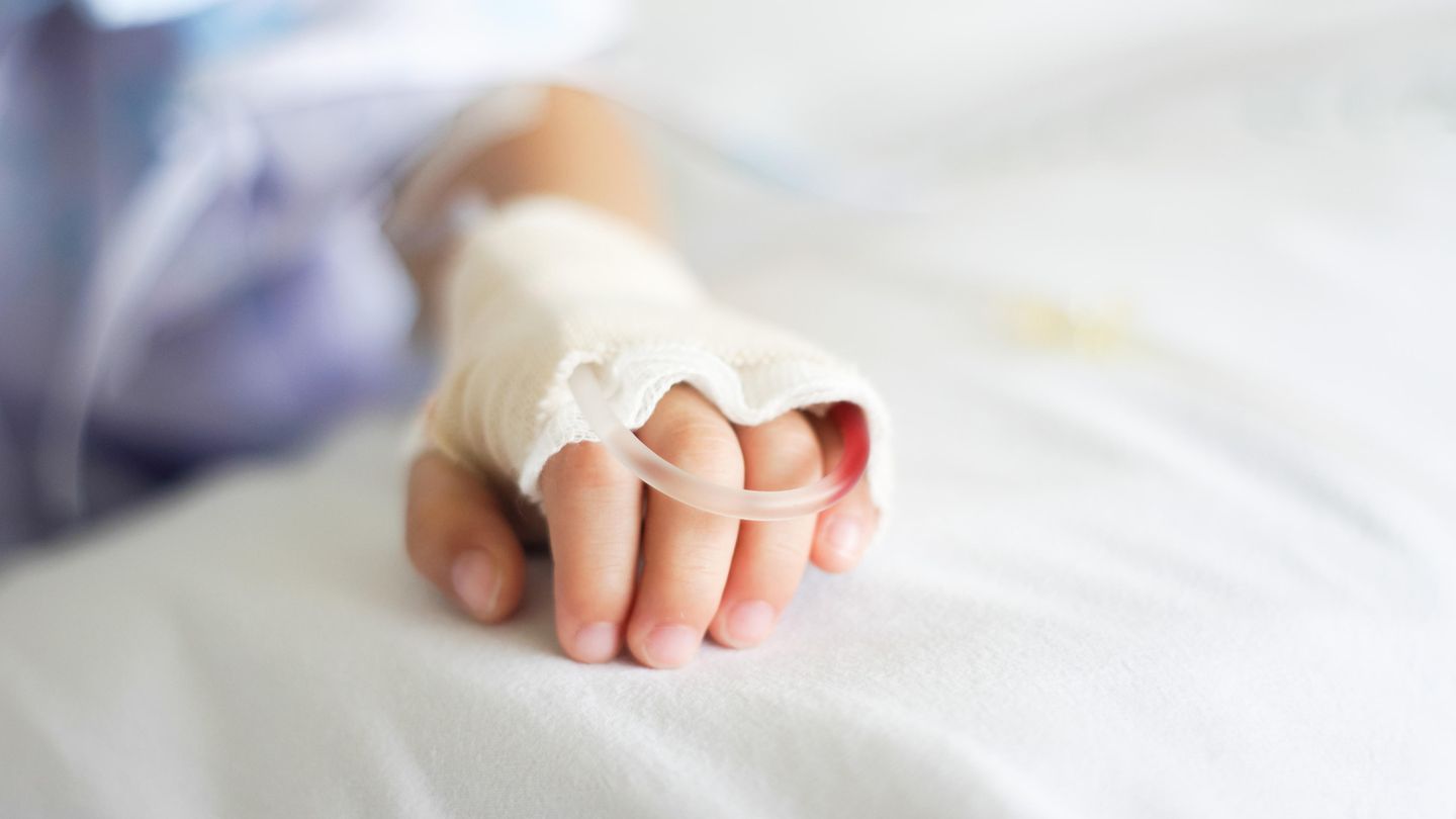 Hand eines Kindes mit Infusion und Verband
