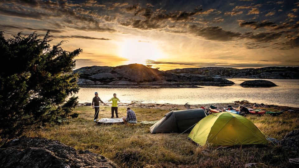 Während die Sonne untergeht, bauen die Kajakfahrer ihre Zelte für die Nacht auf.