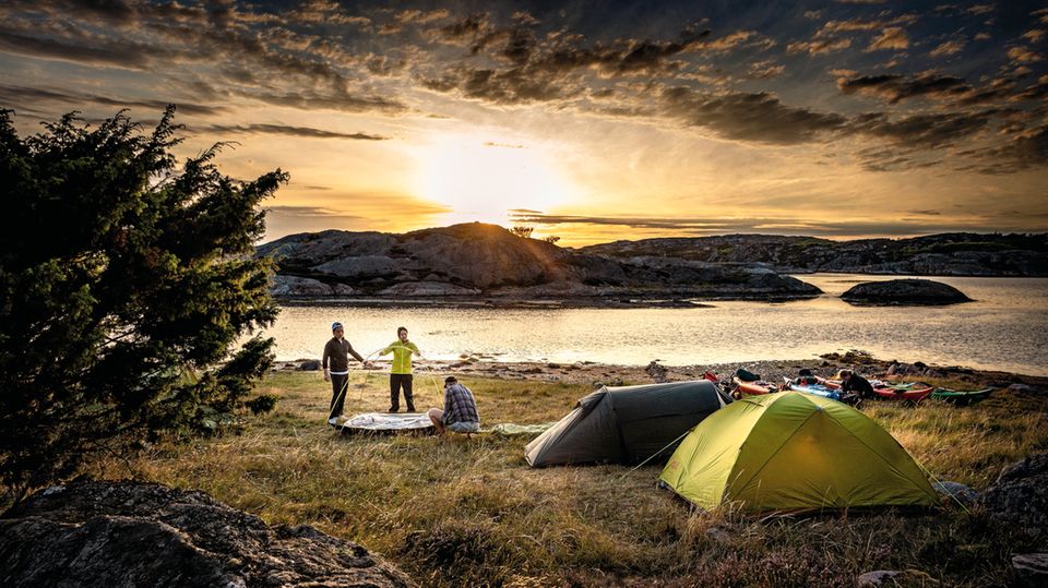 Kajaktour in Schweden: Während die Sonne untergeht, bauen die Kajakfahrer ihre Zelte für die Nacht auf. Während die Sonne untergeht, bauen die Kajakfahrer ihre Zelte für die Nacht auf.