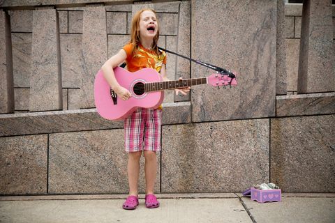 Mächen mit Guitarre singt auf der Straße