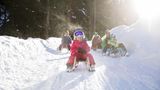 Eine Familie rodelt in einer Winterlandschaft