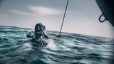 Schatztaucher Andi taucht gerade neben dem Schlauchboot aus der Nordsee auf.