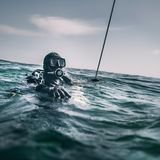 Schatztaucher Andi taucht gerade neben dem Schlauchboot aus der Nordsee auf.