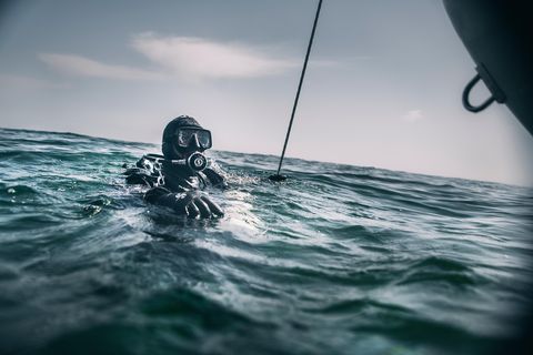 Schatztaucher Andi taucht gerade neben dem Schlauchboot aus der Nordsee auf.
