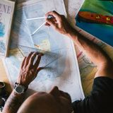 Andi sitzt über einer Seekarte und hat Navigationsbesteck in der Hand.