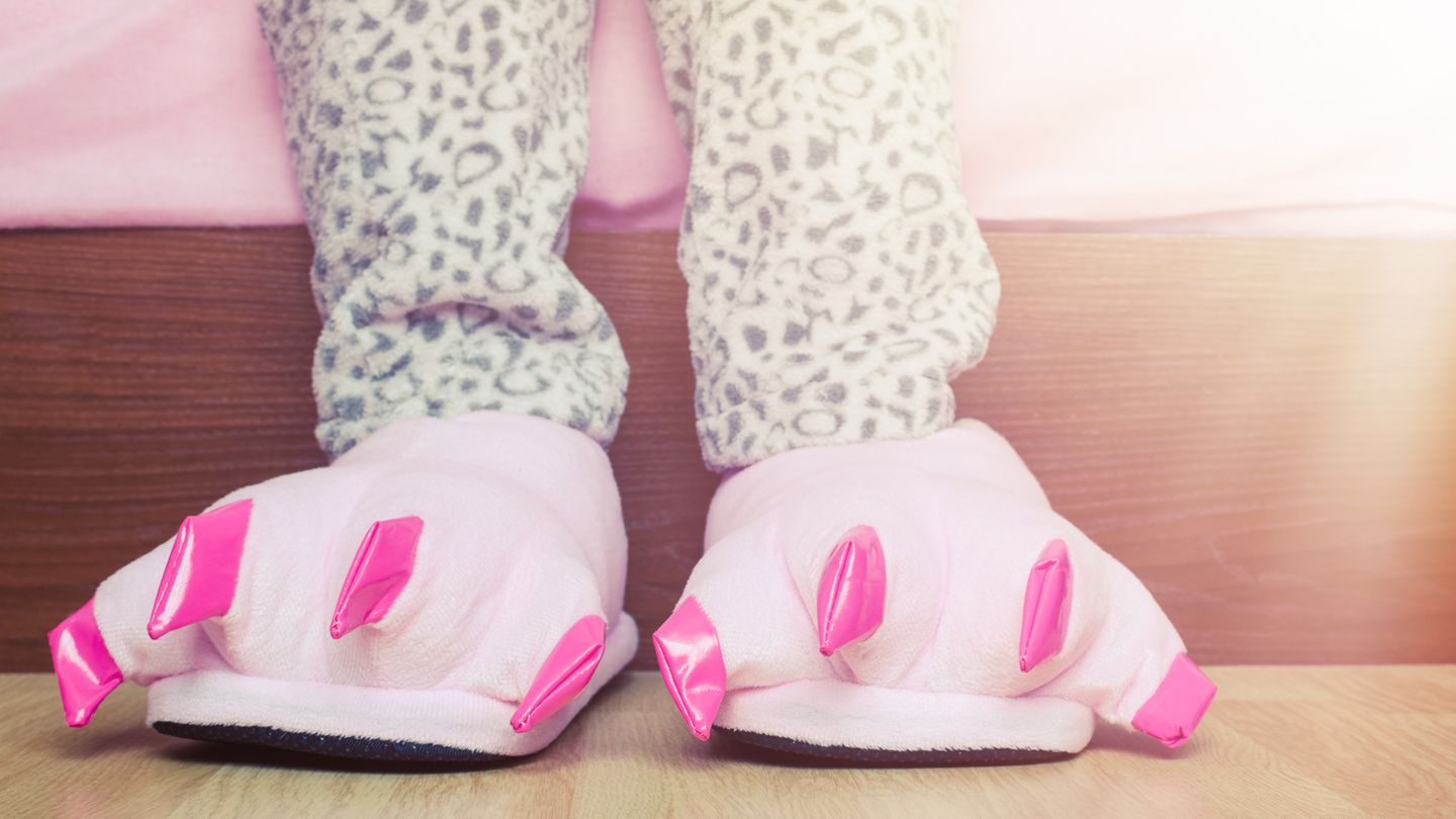 Kinderbeine mit Schlafanzug und Dino-Hausschuhen