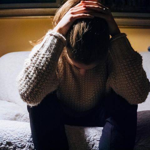 Eine niedergeschlagene Frau sitzt auf dem Bett