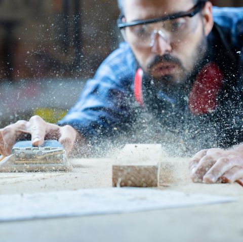 Ein Tischler schleift eine Holzplatte ab