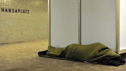 Ein Obdachloser schläft auf einem U-Bahnsteig in Berlin