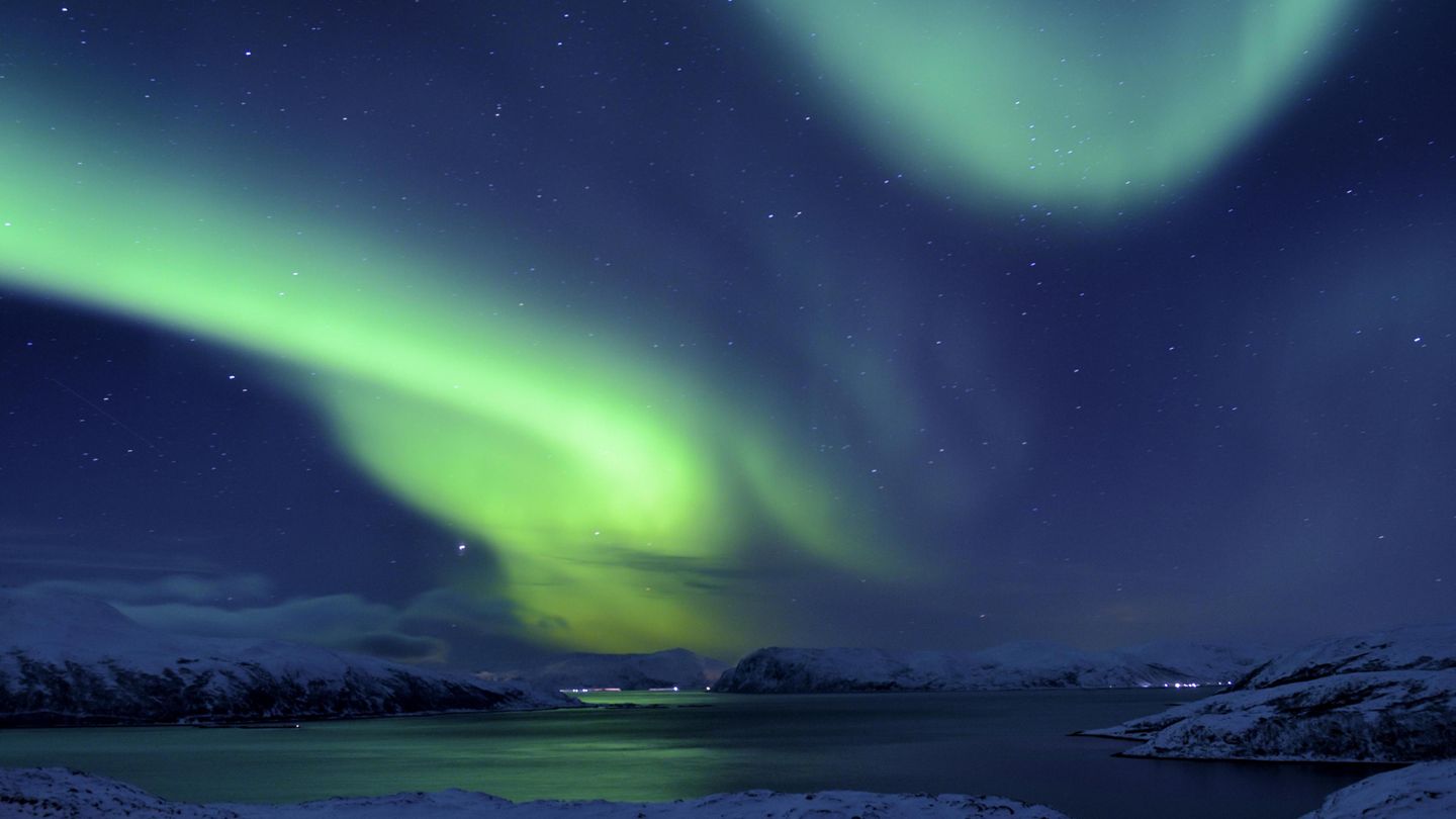Polarlicht über Fjord in winterlicher Landschaft in Sommeroya bei Tromsø