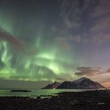 Wie wunderschön sich das Polarlicht über der Bergspitze verhält. Diese Aufnahme entstand auf Haukland, eine der Lofoten-Inseln.