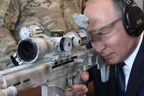 Der russische Präsident Wladimir Putin schießt mit einer neuen Kalaschnikow auf einem Geländer des Waffenherstellers