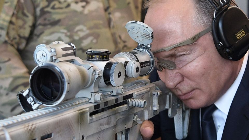Der russische Präsident Wladimir Putin schießt mit einer neuen Kalaschnikow auf einem Geländer des Waffenherstellers