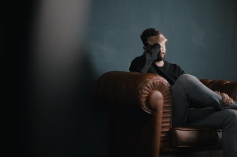 Mann sitzt im Sessel und denkt nach
