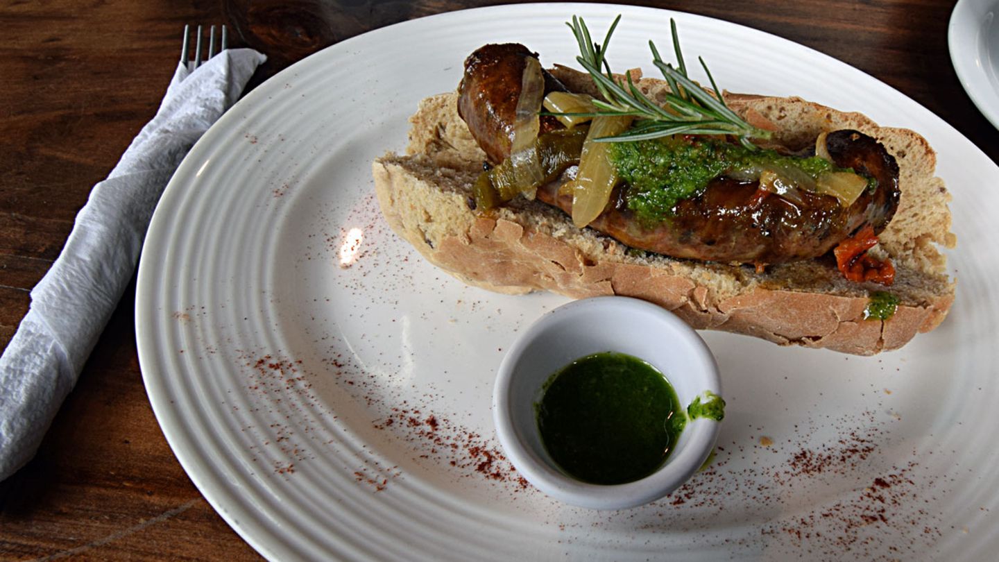 Auch Fleisch und Würste kommen gerne auf den Tisch, wie hier als choripan casero, eine chorizo, eine Wurst im Brot mit grüner chimichurri-Kräutersoße.
