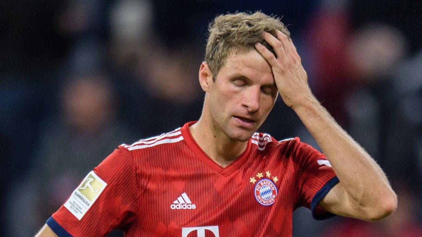 Thomas Müller steht im roten Dress des FC Bayern München auf dem Platz fasst sich mit der linken Hand an den Kopf