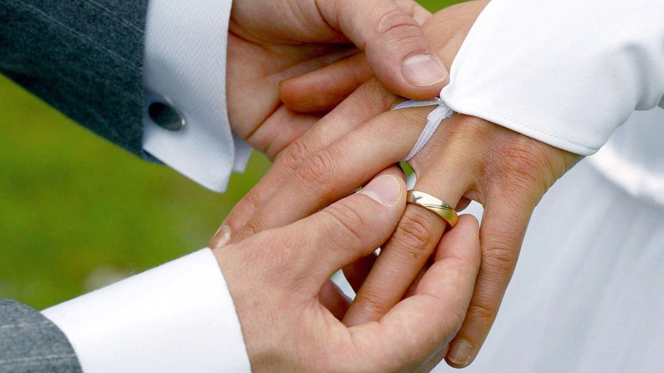Ein steckt seiner Frau bei der Hochzeit den Ring an den Finger Ein steckt seiner Frau bei der Hochzeit den Ring an den Finger