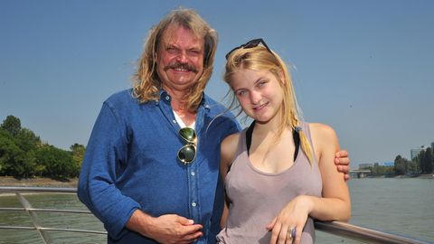 Der Musiker Leslie Mandoki steht an der Rehling eines Schiffes auf einem Fluss, neben sich seine blonde Tochter Julia